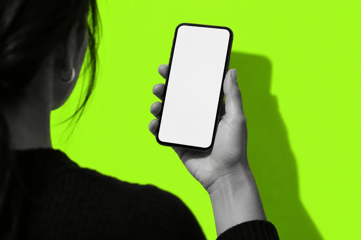 Grayscale hand holding a phone against a vivid lime background