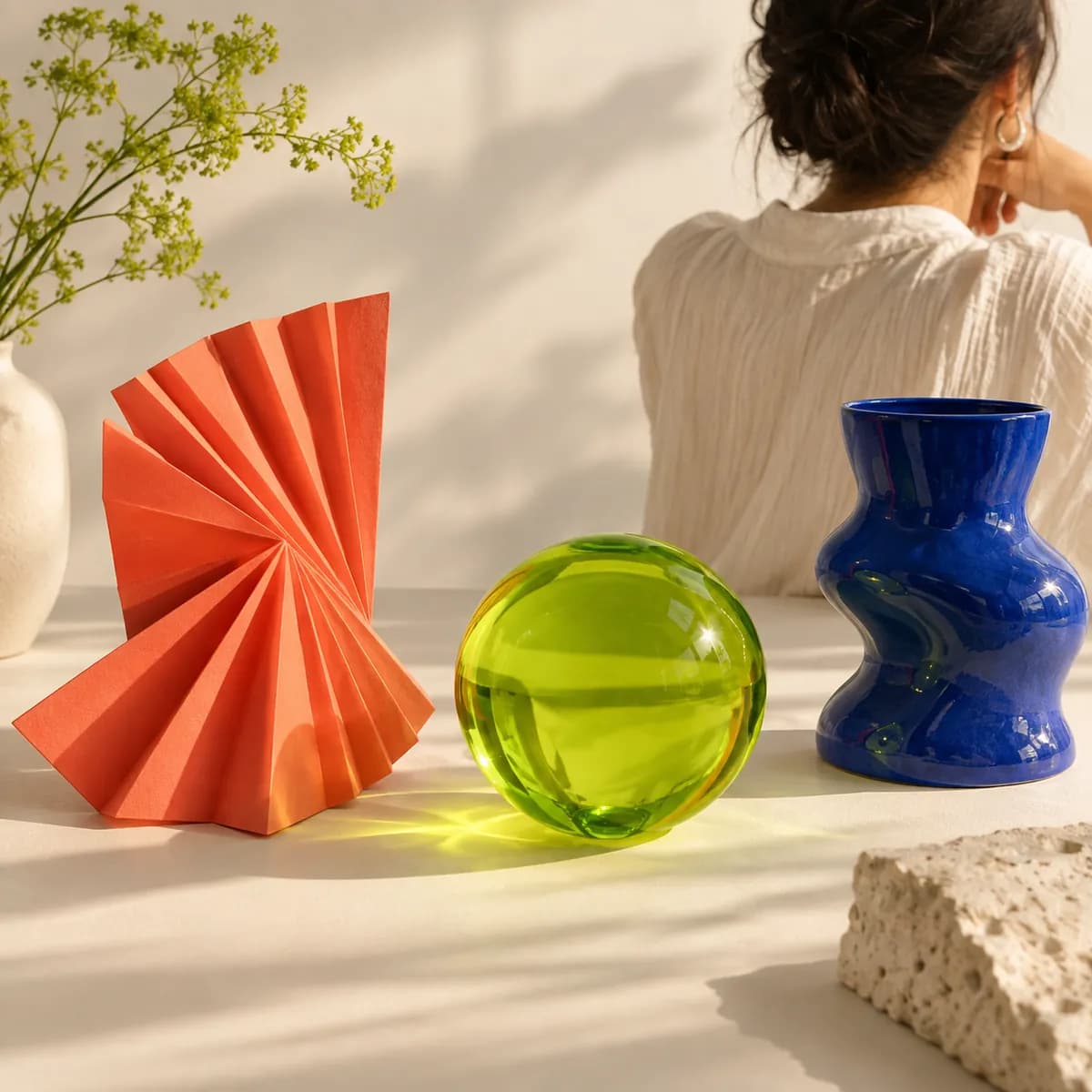 Bright paper sculptures and a lime glass sphere arranged in a creative studio