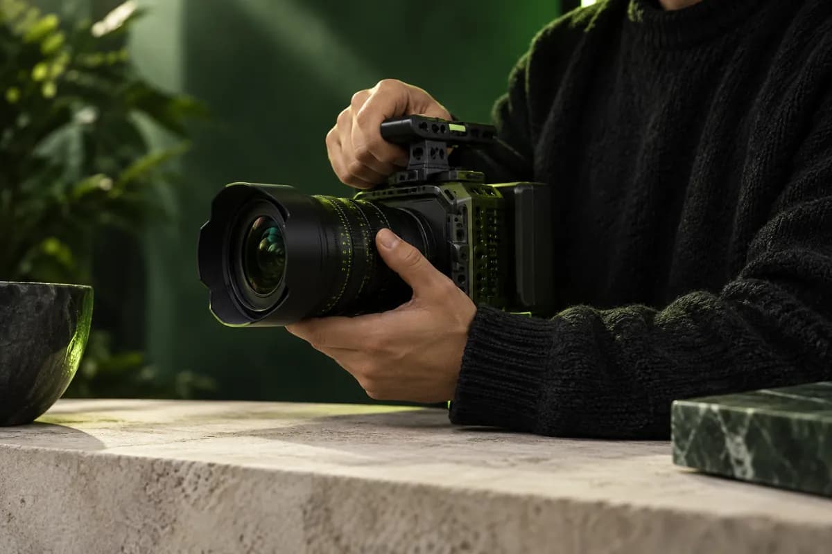 Hands holding a camera in a softly lit green studio