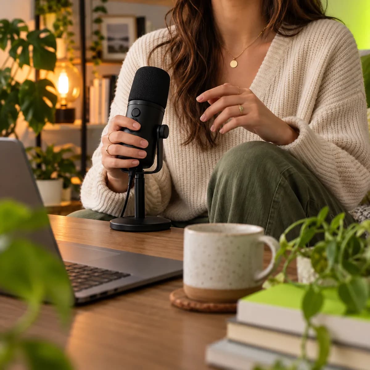 Cropped creator holding a microphone in a warm home studio