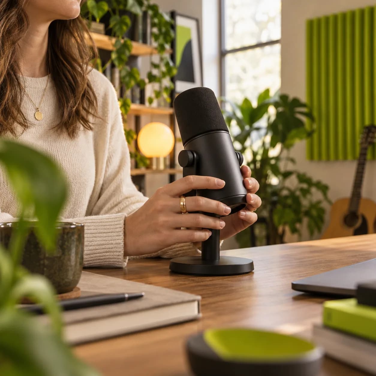 Cropped creator holding a studio microphone in a warm creative workspace